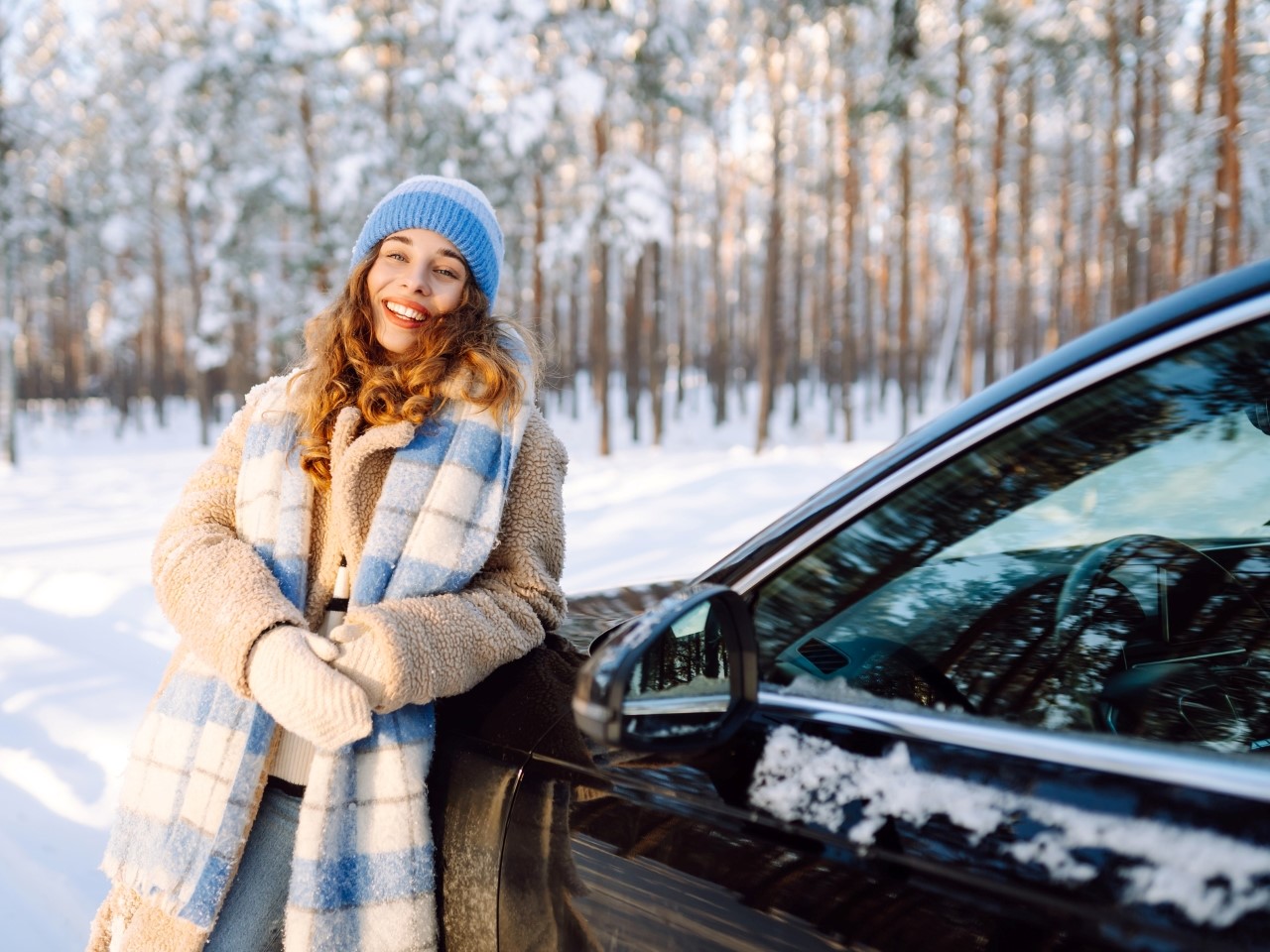 Rõõmus naine on ilusas talvises metsas oma uue autoga.