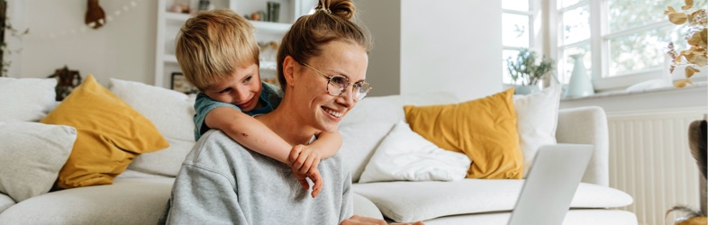 Радостный ребенок с мамой, которая заполняет заявление на страхование квартиры.