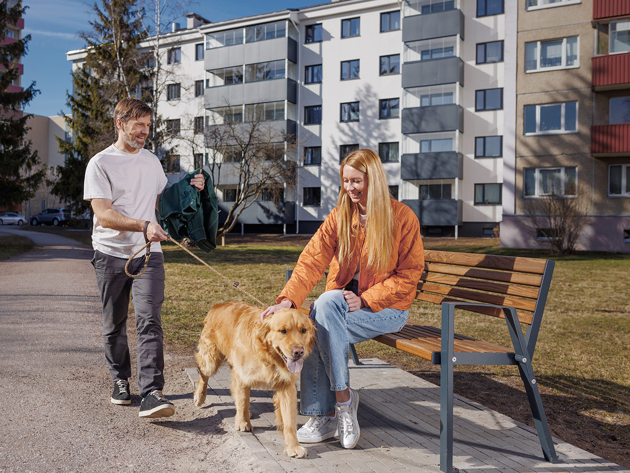 Мужчина и женщина гуляют с собакой по улице