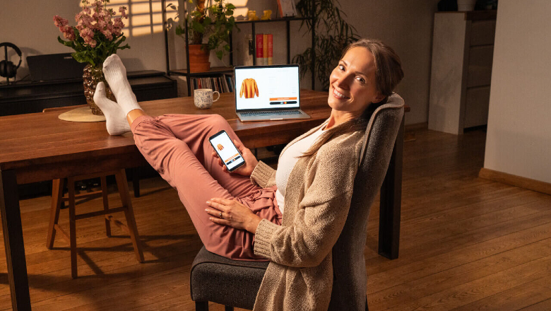 Женщина держит в руке мобильный телефон и совершает оплату в интернет-магазине с помощью платежного решения Click to Pay.