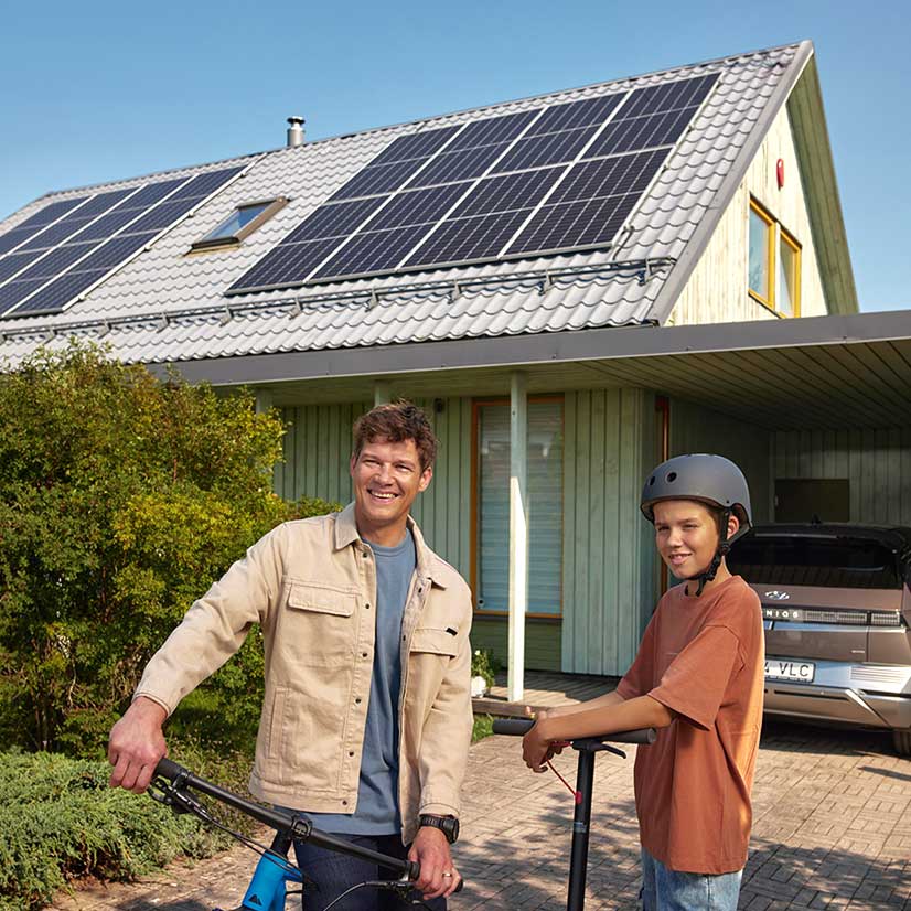 Isa ja poeg seisavad uhkelt oma energiatõhusa maja ees