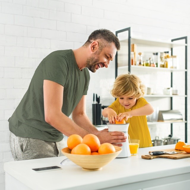 Isa ja poeg pigistavad apelsinidest apelsinimahla välja.